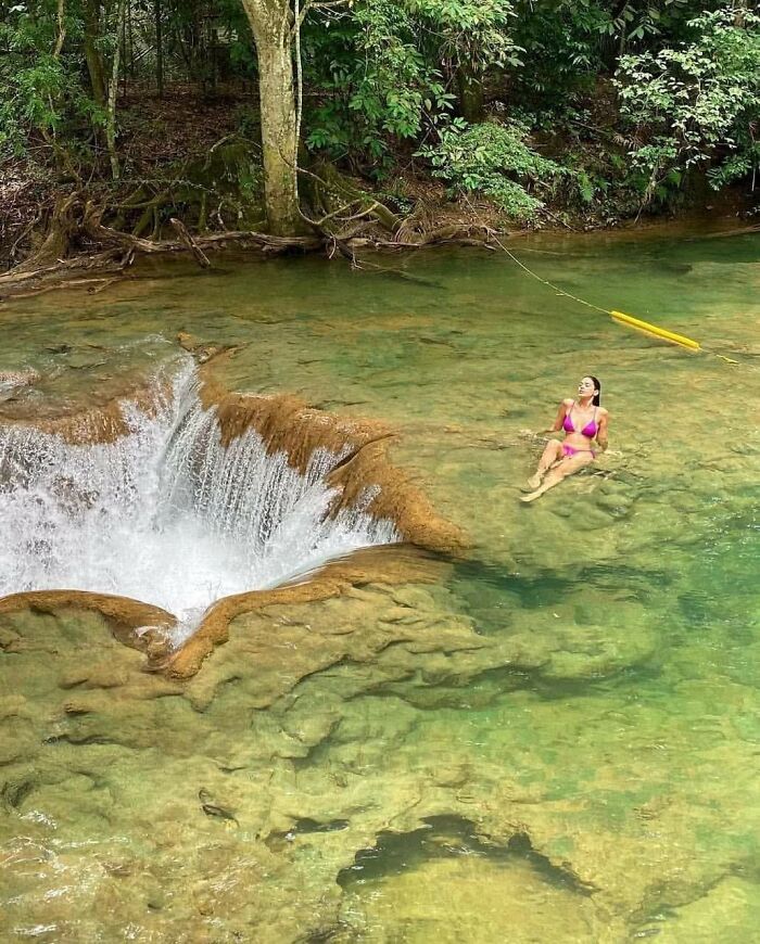 Influencers in public spaces relaxing in natural water near a small waterfall