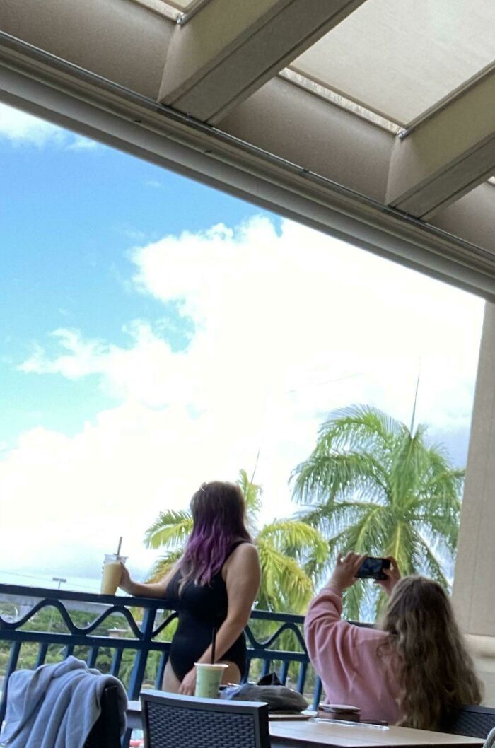 Influencer takes a photo of another woman posing on a balcony in public spaces