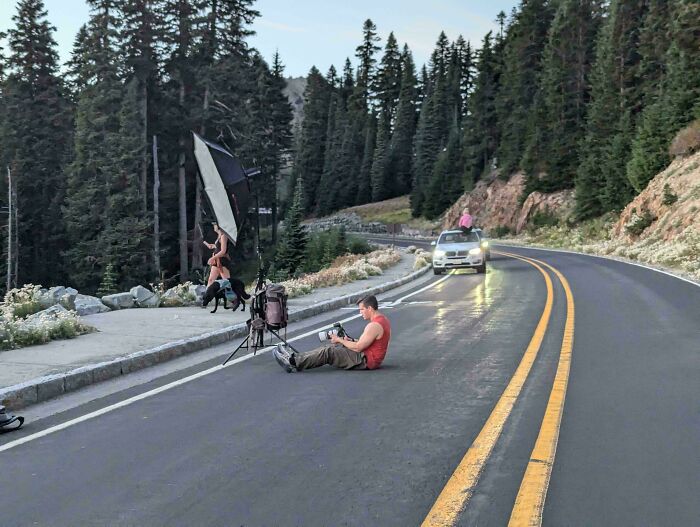 Photographer and influencers using public spaces on a mountain road for a professional photoshoot.