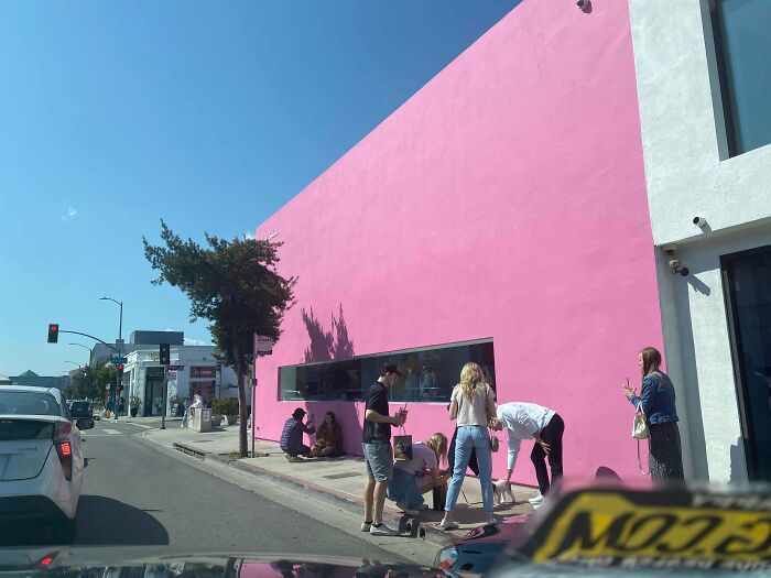 Crowd of influencers gathers to take photos in front of a pink wall in public spaces