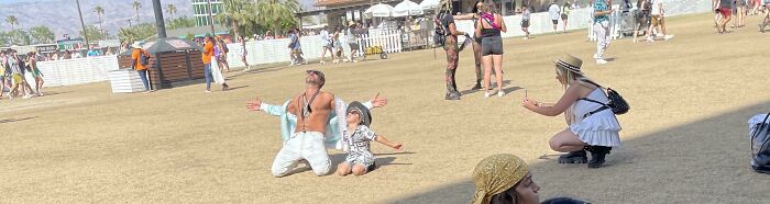 Influencer poses on knees outdoors while another takes photos, treating public spaces like a studio