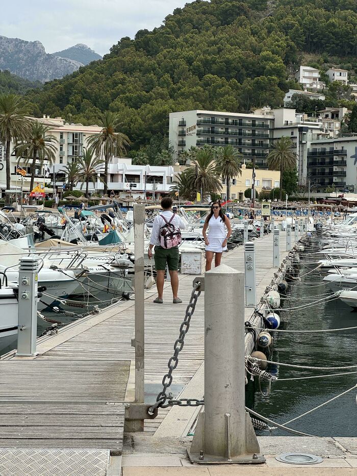 Influencers in public spaces posing for photos on a wooden pier full of boats.