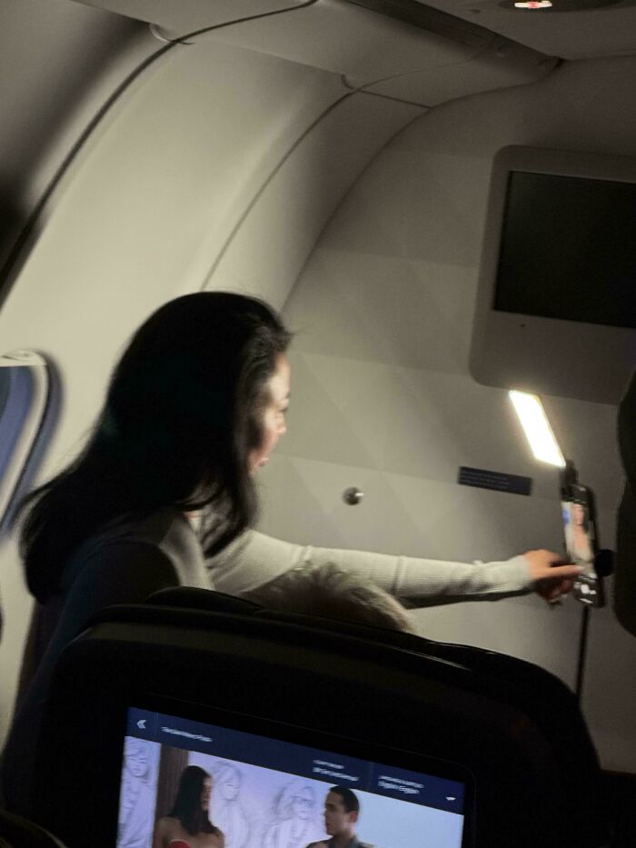Influencers film content inside an airplane cabin using a mobile phone tripod set up.