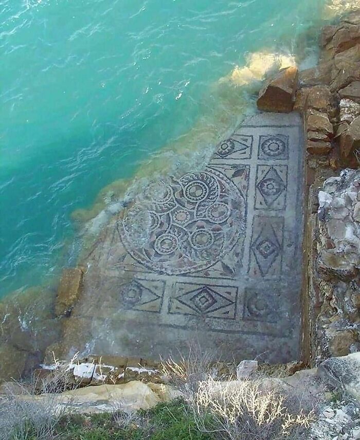 Submerged ancient Roman mosaic floor partially covered by clear turquoise water, showcasing surprising facts about the past.