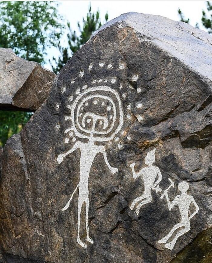 Ancient rock petroglyph depicting humanoid figures and symbols as interesting facts about the past.
