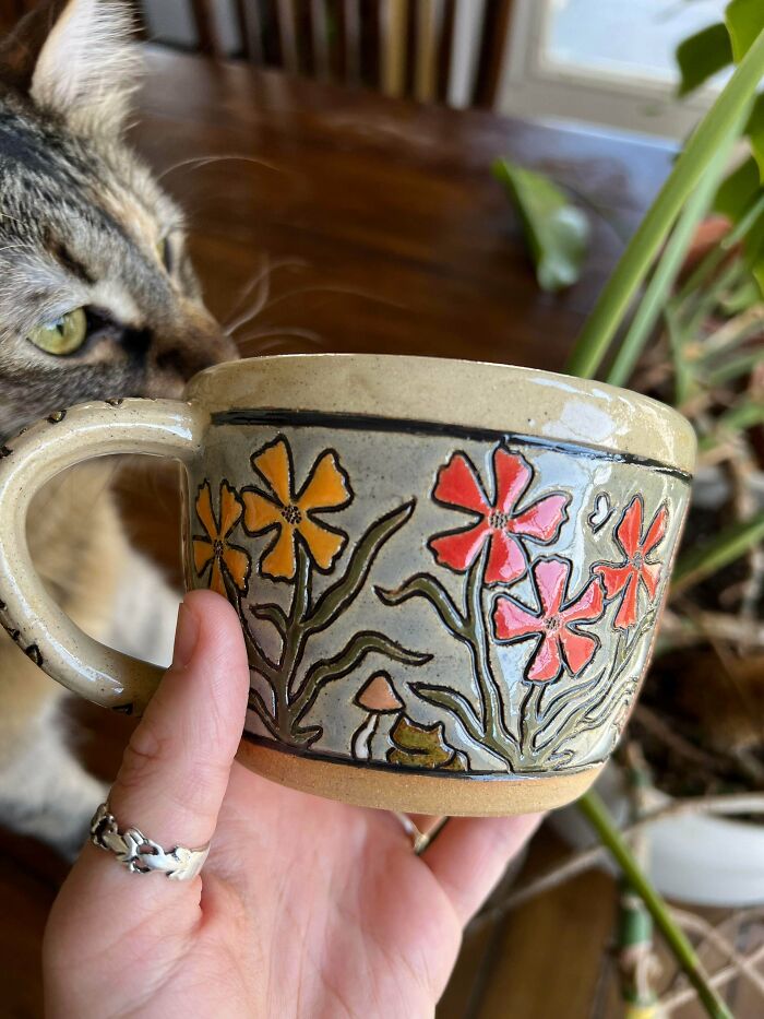 Handcrafted ceramic mug with floral engravings and cat showing beautiful pottery creations