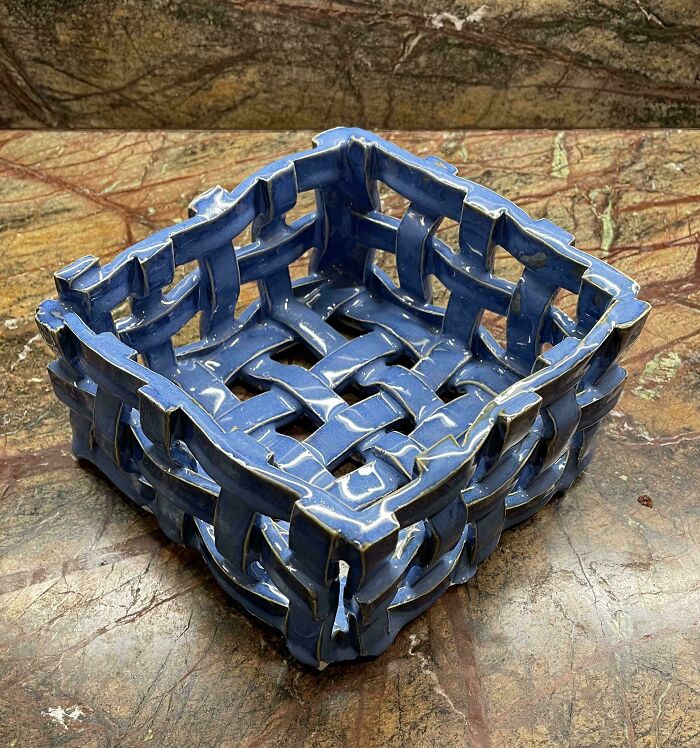 Handcrafted blue woven ceramic basket showcasing unique pottery creations on a marble surface