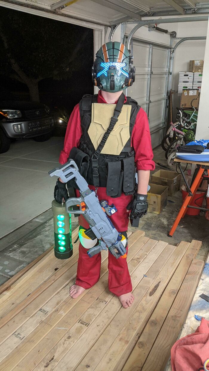 A child in a futuristic video game Halloween costumes outfit holding a toy blaster