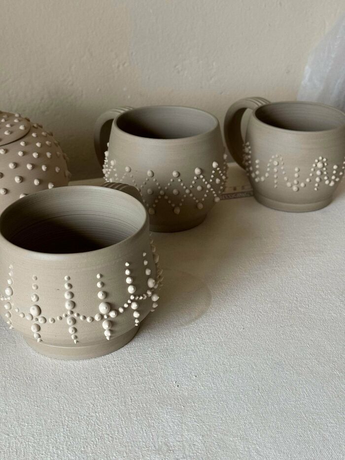 Handcrafted beige clay mugs featuring raised dot details as pottery creations.