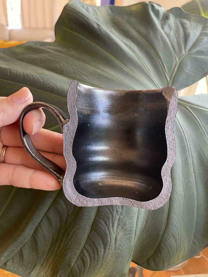 A cross section view of a dark ceramic mug highlighting detailed pottery creations
