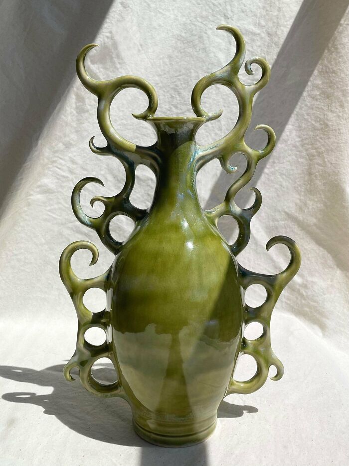 An ornate green ceramic vase with elaborate swirling handles, displaying creative pottery creations.