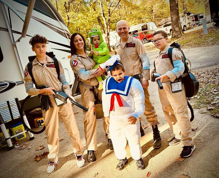 A family dressed as Ghostbusters showing off creative Halloween costumes together outdoors.