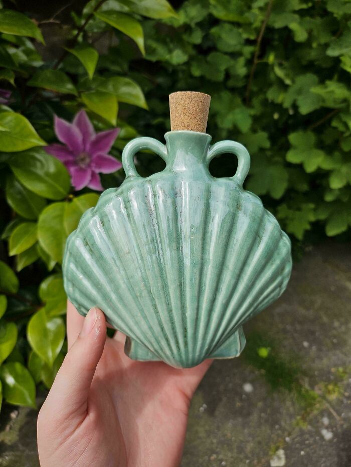 A seashell-shaped green ceramic bottle with a cork stopper, part of novel pottery creations.