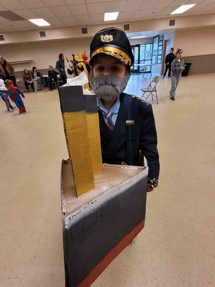 A boy dressed as the Titanic captain inside a cardboard ship for creative Halloween costumes.