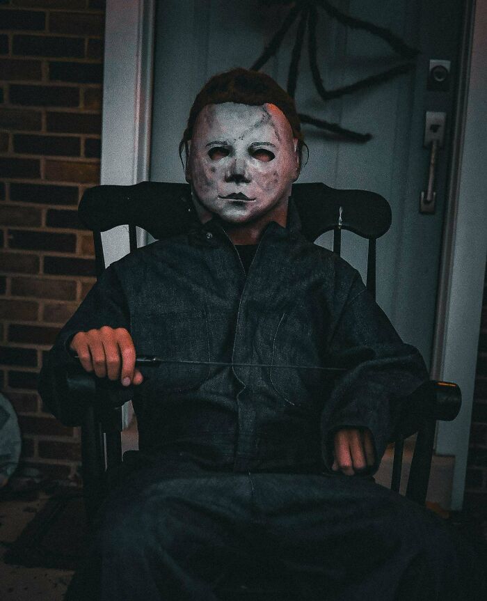 A child wearing a spooky Michael Myers mask sitting in a chair for creative Halloween costumes.