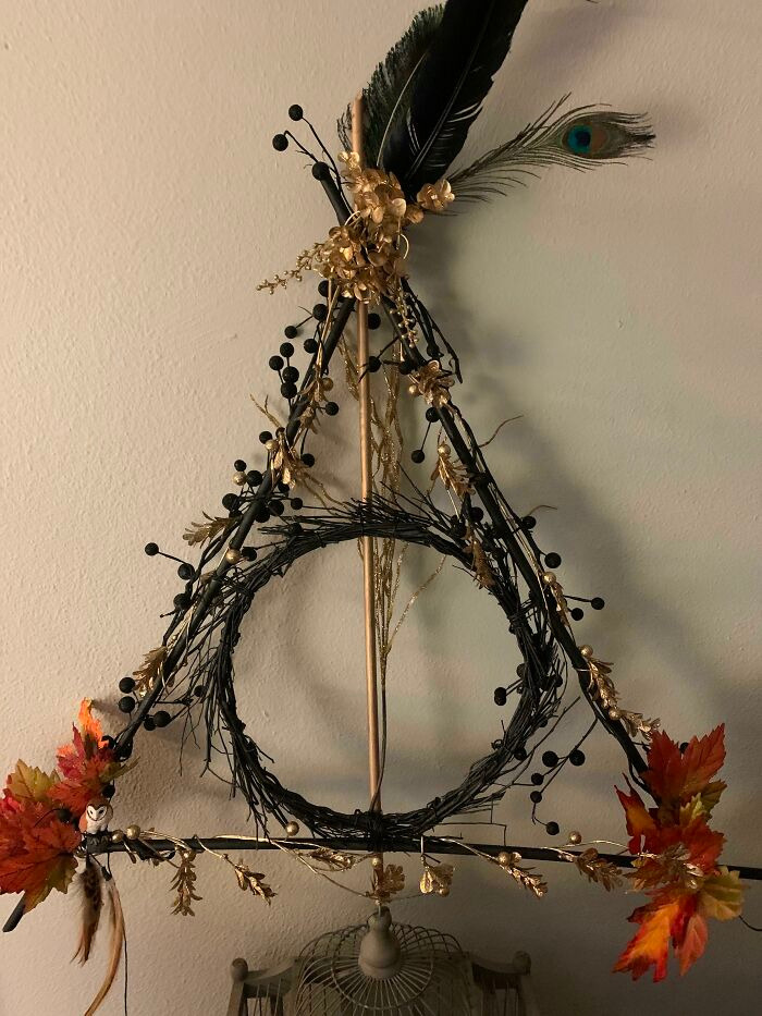 A Deathly Hallows symbol wreath decorated with leaves and feathers for Halloween.