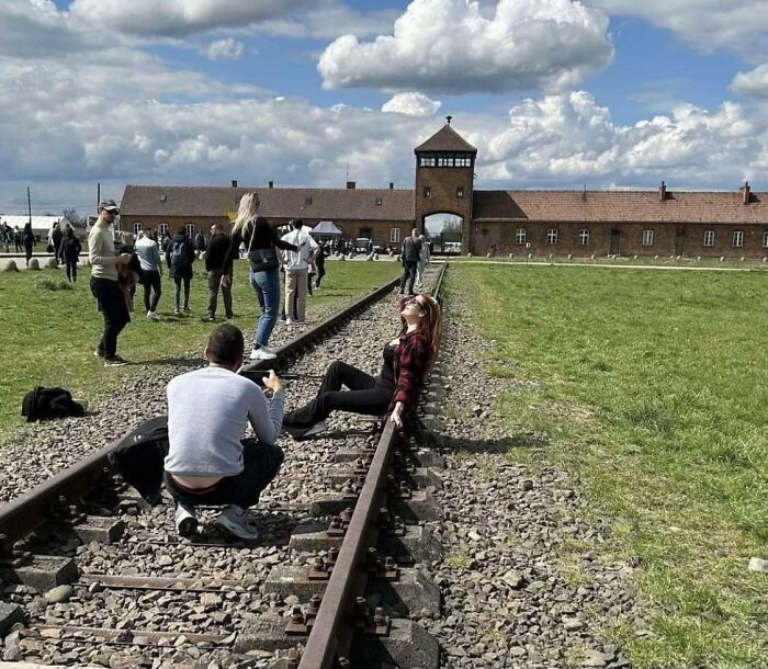 Influencers in public spaces posing in inappropriate photos along train tracks at a memorial site