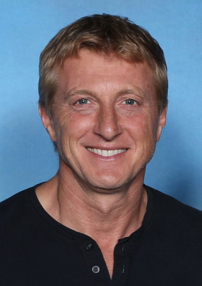 Actor William Zabka smiling in a portrait against a blue background, reflecting his career highlights.