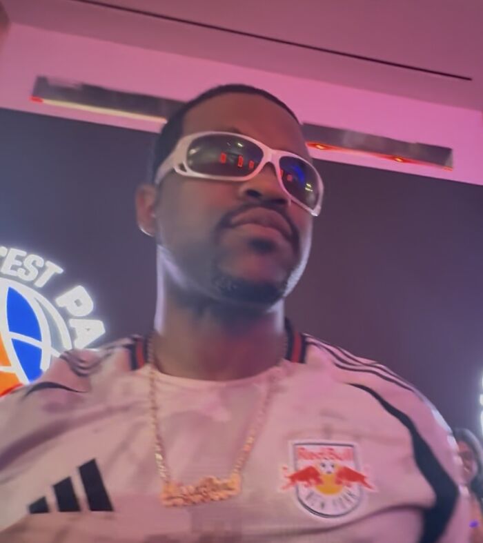 Rapper ASAP Ferg wearing white sunglasses and a sports jersey looking at the camera