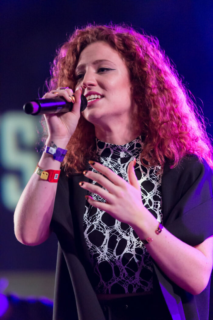 Singer Jess Glynne performing live on stage with a microphone in hand.