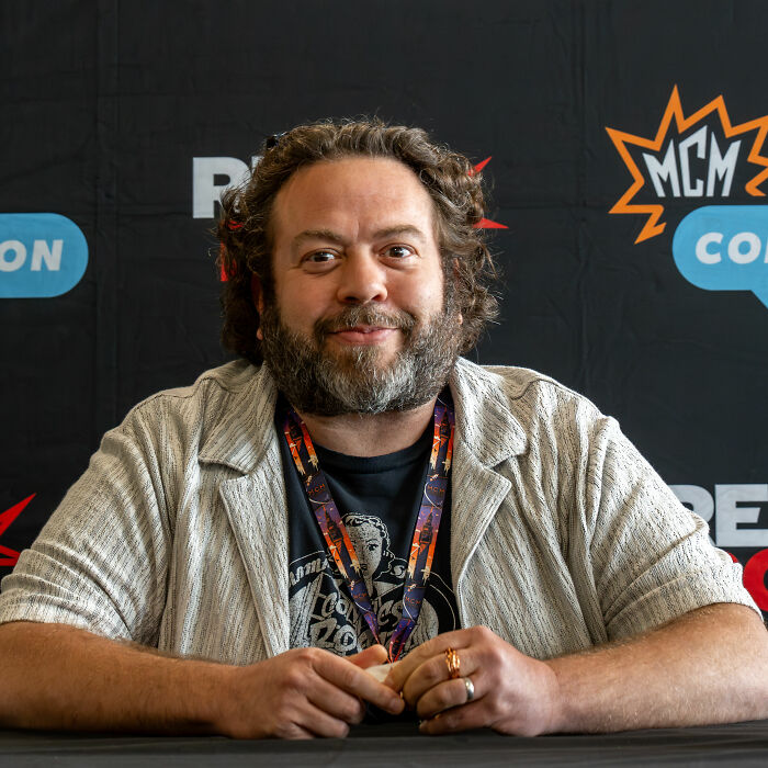 Actor Dan Fogler smiling at a convention table, highlighting his career in entertainment.