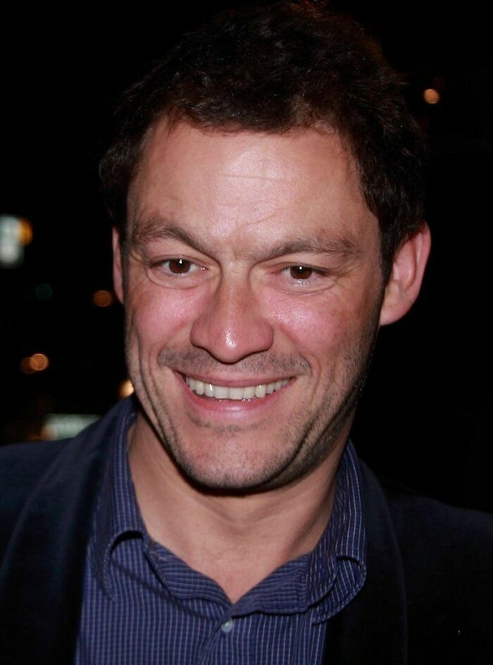 Close-up portrait of actor Dominic West smiling cheerfully.