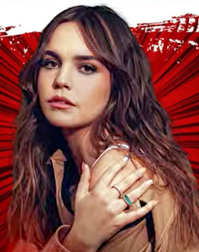 Actress Bailee Madison posing with long wavy brown hair against a stylized red background.
