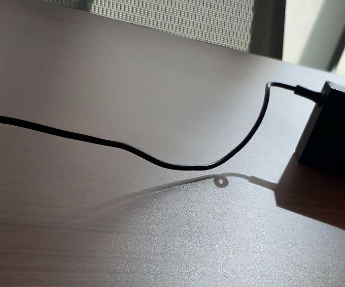Shadow of a charging cable forming a loop on a table mimicking a digital glitch effect