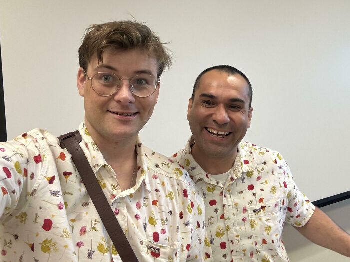 Two men smiling and wearing matching printed shirts indoors