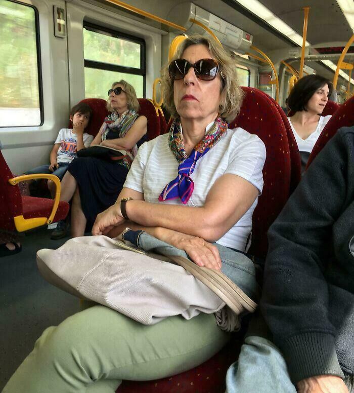 Woman with sunglasses sitting on public transit surrounded by passengers