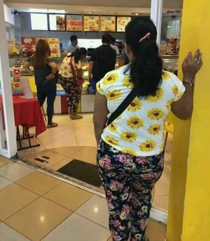 Woman wearing sunflower and floral patterns standing outside food counter glitch