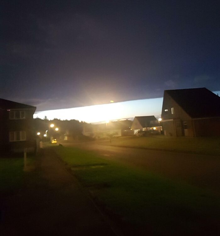 Unexpected bright light breaking through dark clouds over neighborhood resembling a matrix glitch