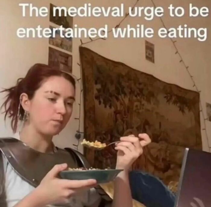 Relatable memes image of a person eating while watching a screen in medieval armor