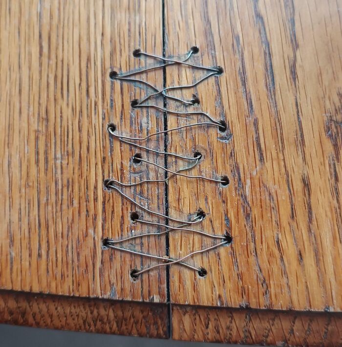 A wooden surface joined together with wire stitches, showcasing a unique way creativity can save money.