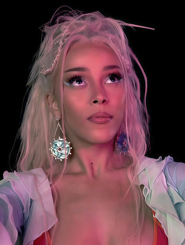 Close-up portrait of Doja Cat with blonde hair and statement earrings looking upward.