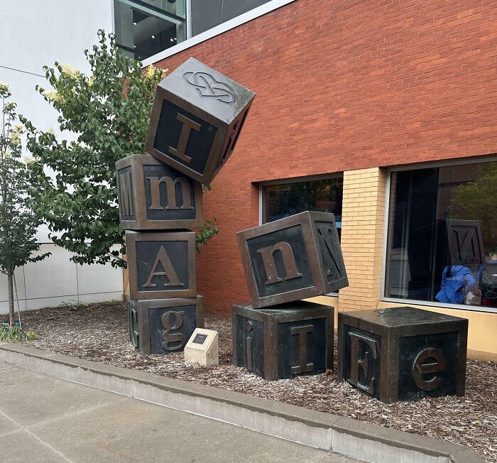 Stacked block sculpture spelling out words with confusing placement, an example of terribly designed signs.