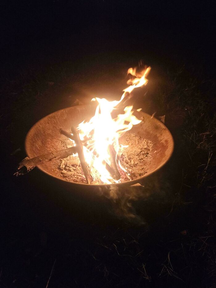 A glowing fire pit at night representing wholesome pics of dads setting up a campfire for family time
