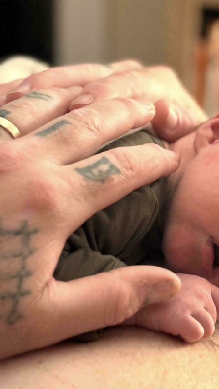 Close up of a father holding his newborn baby, an example of wholesome pics of dads nailing fatherhood.