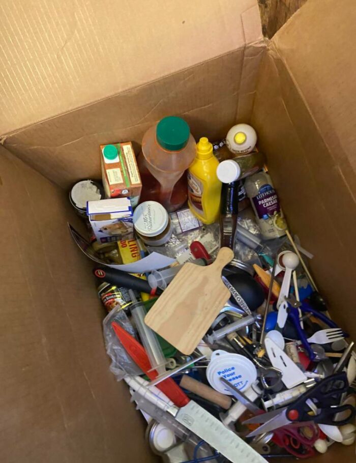 Cardboard box filled with cluttered kitchen utensils and condiments, showcasing things partners do.