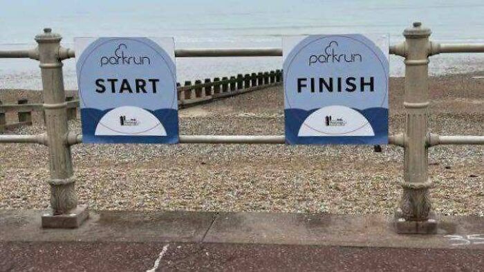 Parkrun start and finish signs placed right next to each other on a fence