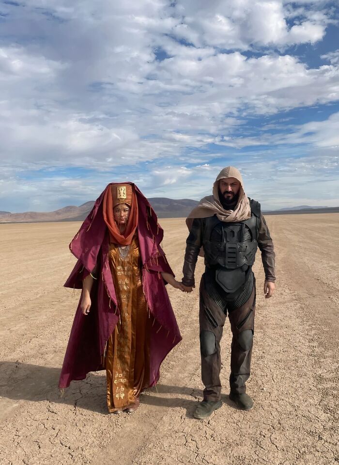 Man and woman in elaborate desert sci-fi outfits, showcasing funny cool Halloween couples costumes in a dry landscape.