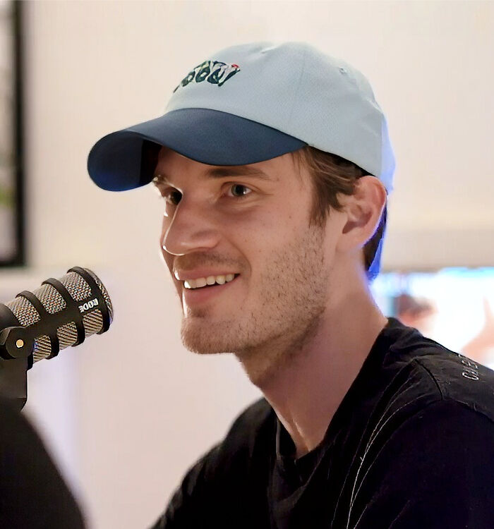 PewDiePie bio and career highlights featured as Felix Kjellberg smiles into a microphone wearing a baseball cap