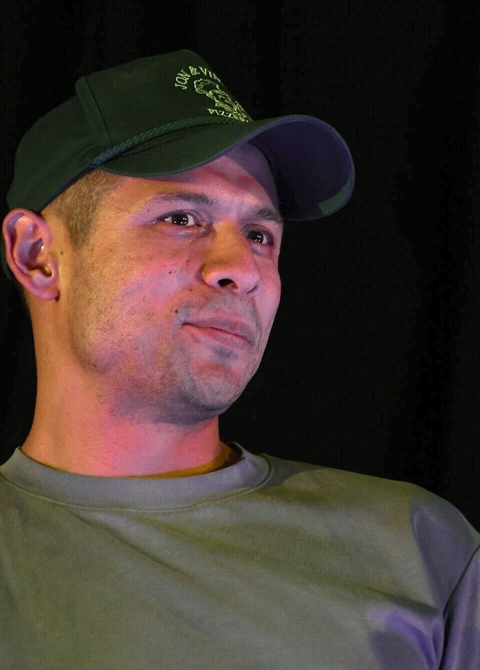 Close up portrait of actor David Castañeda wearing a green baseball cap and shirt.