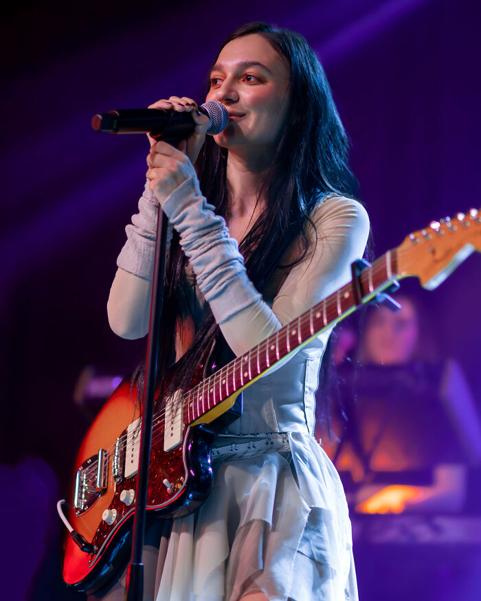 Singer Daya performing live on stage with an electric guitar and microphone.