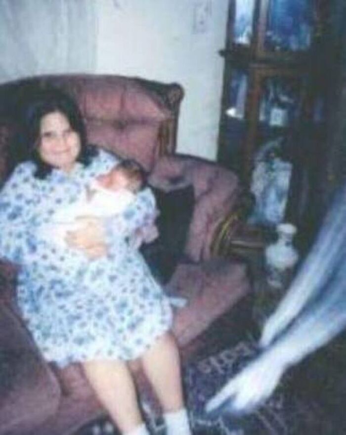 Eerie real-life photo of a mother and baby with a blurry ghostly figure resembling a horror movie