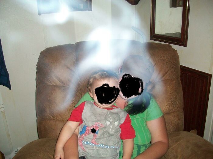 Eerie bright light streak over a mother and toddler sitting indoors, like a scene from a horror movie.