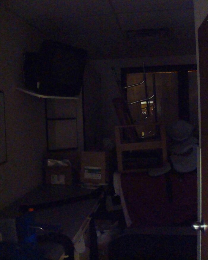 A dark storage room with stacked furniture looking like a creepy scene from a horror movie.