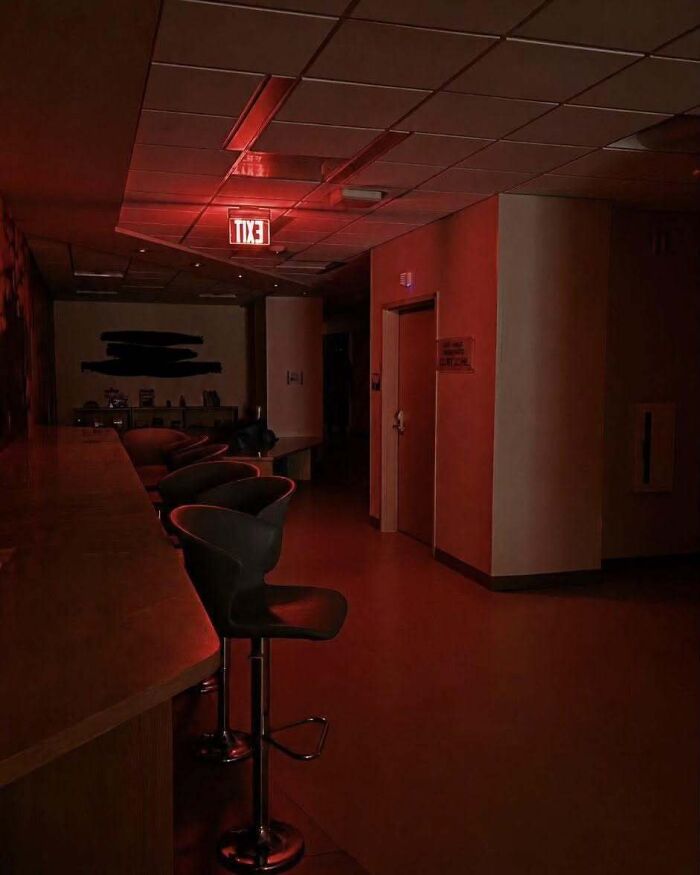 A dim hallway lit with eerie red lights in a scene resembling real-life photos from a horror movie.