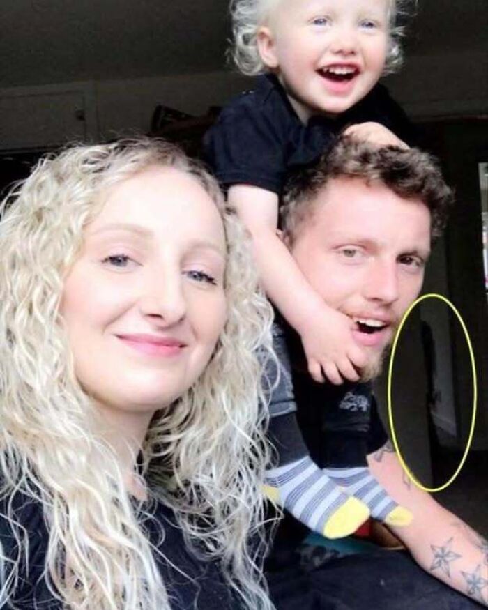 A family photo with a mysterious dark silhouette highlighted in the doorway behind them