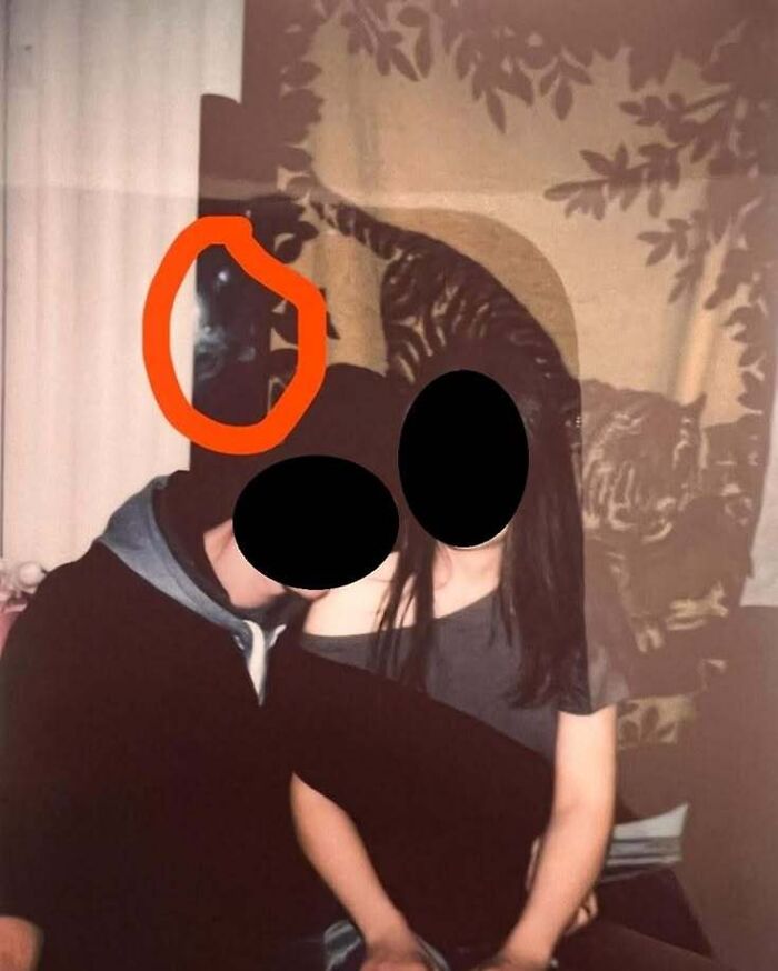 Flash photo of couple with a dark figure highlighted in red, like a real-life horror movie scene